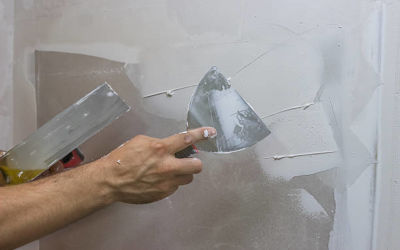 man hand with trowel plastering a wall, skim coating plaster walls