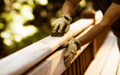 carpenter sanding cedar wood deck before staining.
