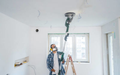 man using vacuum sanding machine on ceiling and walls