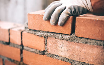 close up of industrial bricklayer installing bricks on construction site