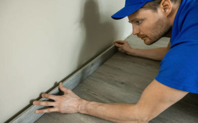 worker installing skirting board, baseboard by the wall